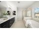 Bright bathroom featuring a dual sink vanity, soaking tub, and walk-in shower with window views at 1922 Perry Nw Blvd, Atlanta, GA 30318