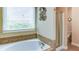 Bright bathroom featuring a soaking tub under a window and a glass-enclosed shower at 4084 Fort Sumter Nw Lndg, Acworth, GA 30101