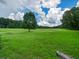 Large green land featuring a mature tree and providing ample space for recreation or development, and a rustic wooden fence at 1980 Deco Dr, Kennesaw, GA 30144
