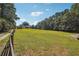 Expansive green backyard bordered by trees, and a white home is visible in the distance surrounded by a wooden fence at 3842 Ernest W Barrett Sw Pkwy, Marietta, GA 30064