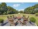 Outdoor fire pit area with chairs, gravel, potted plants, and views of the surrounding green land and treeline at 3842 Ernest W Barrett Sw Pkwy, Marietta, GA 30064