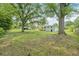Large grassy backyard with mature trees and a view of the back of the house at 1261 Cliffwood Se Dr, Smyrna, GA 30080