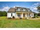 Bright white farmhouse featuring a covered front porch with stylish landscaping and a lush green lawn at 3508 Cox Cemetery Rd, Social Circle, GA 30025