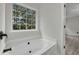 Bright bathroom features a soaking tub under a large window with a view at 3943 Alexandra Oak Ct, Suwanee, GA 30024