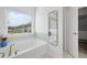 Bright bathroom featuring a large soaking tub under a window and a mirror at 1998 Lakeview Bend Way, Buford, GA 30519