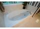 Close-up of a large white bathtub with jets, surrounded by tile and striped wallpaper at 1703 Rifle Sw Rdg, Marietta, GA 30064