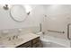Bright bathroom featuring white tiled walls, a round mirror, and a shower/tub combination at 235 The Prado N, Atlanta, GA 30309
