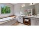 Bright bathroom with a large soaking tub, double vanity, and a window with wooded views at 453 Carter Se Ave, Atlanta, GA 30317