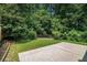 Private backyard with lush greenery, small deck, and a concrete patio area at 85 Brushed Ives Ct, Lawrenceville, GA 30045