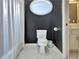 Bathroom with a toilet, shower, and oval window, featuring dark walls and white tile flooring at 104 Hidden Springs Ln, Peachtree City, GA 30269