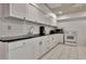 Bright kitchen featuring white cabinets and appliances and black countertops at 104 Hidden Springs Ln, Peachtree City, GA 30269