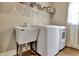 Bright laundry room with sink, washing machine, dryer, and overhead shelving at 104 Hidden Springs Ln, Peachtree City, GA 30269