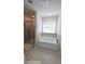 Bright bathroom featuring a white soaking tub next to a glass-enclosed shower and tiled walls at 2757 Malton Way, Loganville, GA 30052
