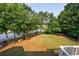 Spacious backyard featuring a serene pond with mature trees, a trampoline and lush green lawn space at 652 Pathview Ct, Dacula, GA 30019