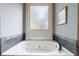 A soaking tub is situated below a frosted window allowing privacy and soft natural light in the bathroom at 652 Pathview Ct, Dacula, GA 30019