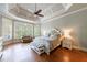 A spacious main bedroom with hardwood floors, decorative trey ceiling, and a sitting area with lots of windows at 652 Pathview Ct, Dacula, GA 30019