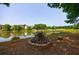 Charming scene of a pond with a cozy fire pit, surrounded by trees and neighborhood homes at 652 Pathview Ct, Dacula, GA 30019