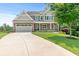 Charming two-story home with a well-manicured lawn and a long driveway leading to an attached two-car garage at 466 Sweet Apple Ln, Buford, GA 30518