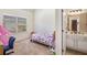 A cozy bedroom features a patterned bedspread, a window with blinds, and a partial view of an adjacent bathroom at 4854 Cathedral Ct, Powder Springs, GA 30127