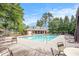 A community pool with lounge chairs and tables surrounded by lush trees under a sunny, partly cloudy sky at 4854 Cathedral Ct, Powder Springs, GA 30127