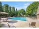 Community pool with lounge chairs and tables surrounded by lush trees on a sunny day at 4854 Cathedral Ct, Powder Springs, GA 30127