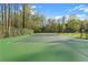 Full tennis court view surrounded by a tall fence and green trees at 860 Crest Valley Dr, Sandy Springs, GA 30327