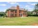 Brick home featuring a well-manicured lawn, a patio, and mature trees surrounding the property at 125 Ancient Oak Ln, Stockbridge, GA 30281