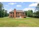 Brick home featuring a well-manicured lawn, a patio, and mature trees surrounding the property at 125 Ancient Oak Ln, Stockbridge, GA 30281