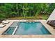Aerial view of a private in-ground pool, spa, and lush green backyard surrounded by stone tile at 131 Forsyth Park Ln, Woodstock, GA 30188