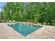 Relaxing in-ground pool featuring stone tile, waterfalls, and views of lush green surroundings at 131 Forsyth Park Ln, Woodstock, GA 30188