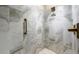 Close-up of the shower featuring marbled walls, pebble base, and bronze fixtures at 131 Forsyth Park Ln, Woodstock, GA 30188