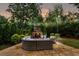 Cozy stone fireplace and seating area are beautifully illuminated in the backyard at dusk at 2579 Lulworth Ln, Marietta, GA 30062