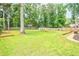 Large backyard with mature trees, lush green grass, a fire pit, and patio seating at 2735 Jims Ne Rd, Marietta, GA 30066
