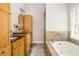Relaxing bathroom featuring soaking tub, travertine tile, and wood cabinetry at 2735 Jims Ne Rd, Marietta, GA 30066
