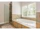 Spa-like bathroom featuring soaking tub, glass enclosed shower, and travertine tile at 2735 Jims Ne Rd, Marietta, GA 30066