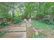 Relaxing backyard featuring a stone walkway leading to a firepit, surrounded by mature trees and lush greenery at 1267 Thomas Rd, Decatur, GA 30030
