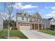 Two-story home featuring a brick and siding facade, dormer windows, and an attached two-car garage at 313 Foxglove Way, Mcdonough, GA 30253