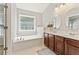 Bathroom featuring dual vanities, modern tub, large window, and neutral decor at 3328 Chastain Gardens Nw Dr, Kennesaw, GA 30144