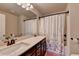 This bathroom has a large vanity with dark wood cabinets, a framed mirror, and shower with decorative curtain at 5016 Garrett Ct, Alpharetta, GA 30005
