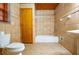 A tiled bathroom features a bathtub, sink, and toilet, all in warm, neutral colors at 360 Parr Farm Rd, Covington, GA 30016