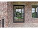 Covered porch with brick flooring, black railings, and view of the front yard at 6120 Hutchins Dr, Buford, GA 30518