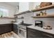 Well-lit kitchen with stainless steel oven, coffee maker, dark cabinets, and natural wood floating shelves at 1168 Mado Loop, Chattahoochee Hills, GA 30268