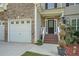 Inviting front entrance with a decorative door, landscaped garden, and a two-car garage on a sunny day at 7052 Camp Falls Ct, Winston, GA 30187