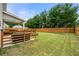 Large, fenced backyard with lush green grass, a covered patio, and mature trees at 2680 Lower Village Dr, Ellenwood, GA 30294