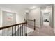 Upstairs hallway showcasing the railing, plush carpet, a window, and three doorways at 2680 Lower Village Dr, Ellenwood, GA 30294