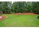 Spacious backyard featuring lush green lawn, landscaping, and mature trees at 2688 Hidden Falls Ne Dr, Buford, GA 30519