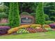 The entrance to Hidden Falls features a sign, trees, and lots of colorful flowers at 2688 Hidden Falls Ne Dr, Buford, GA 30519