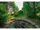 Backyard features stone-lined fire pit, various shrubs, and scattered trees at 5223 Willow Ridge Dr, Woodstock, GA 30188