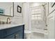 Bathroom featuring marble tile, brass fixtures, a blue vanity, a tub and shower combination, and natural light at 879 Wildwood Ne Rd, Atlanta, GA 30324