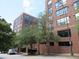 Exterior view of a red brick building with many windows and some trees in front on a partly cloudy day at 115 W Peachtree Nw Pl # 702, Atlanta, GA 30313